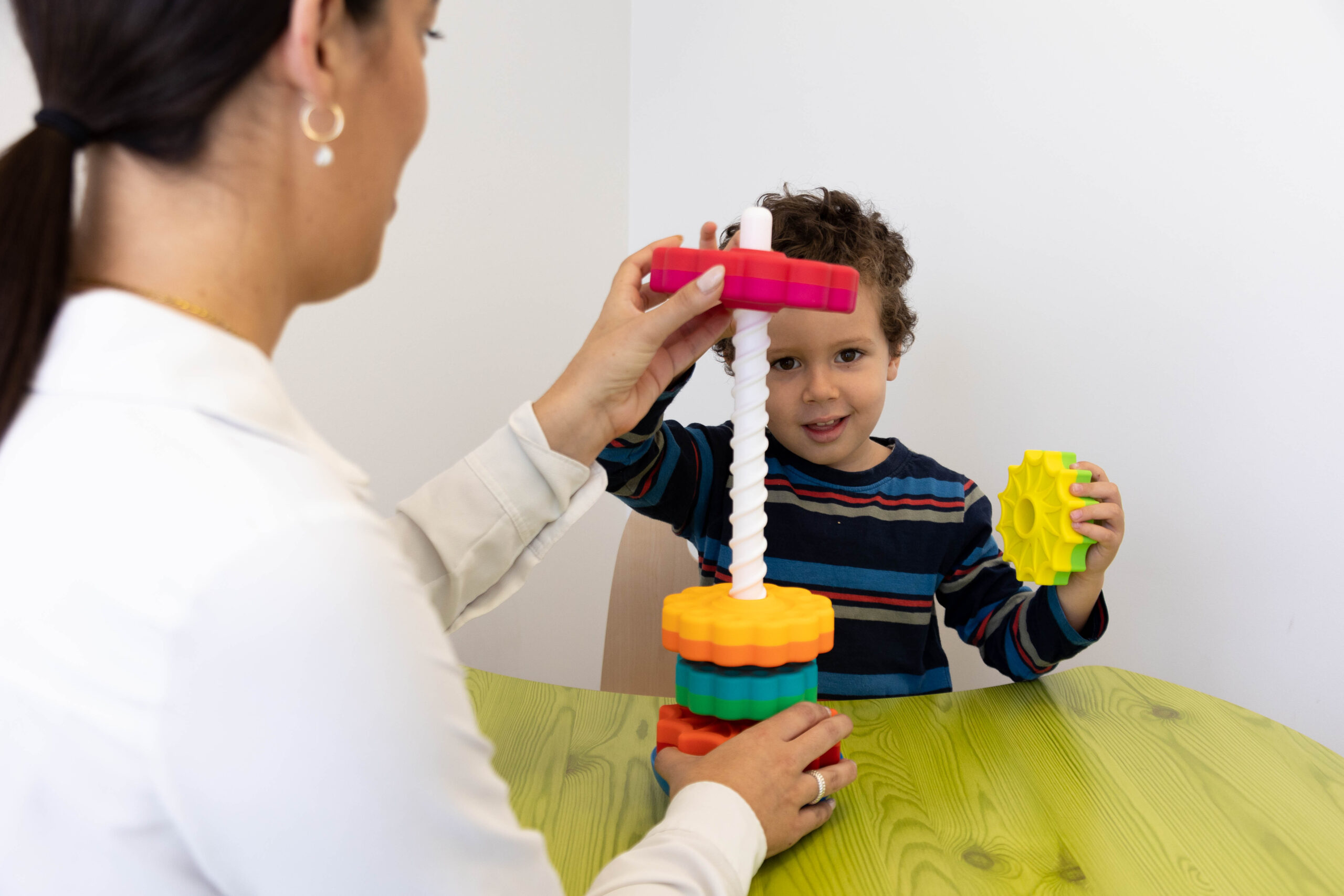 Woman and boy build with colorful gears on a table.