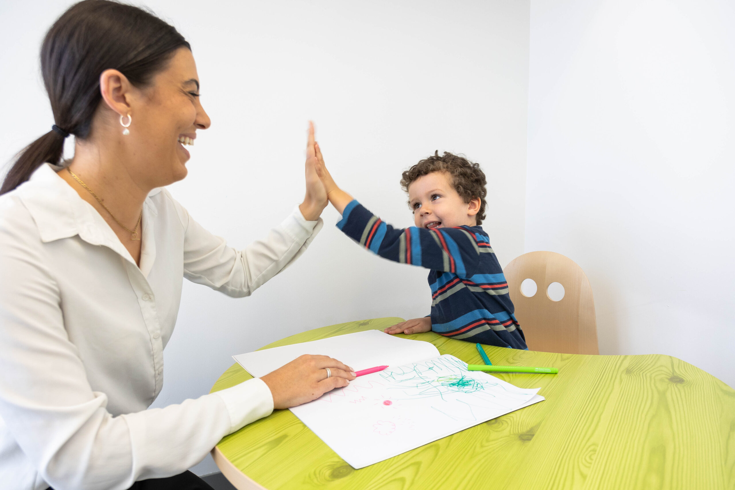 Woman and boy joyfully give each other a high-five during an activity.