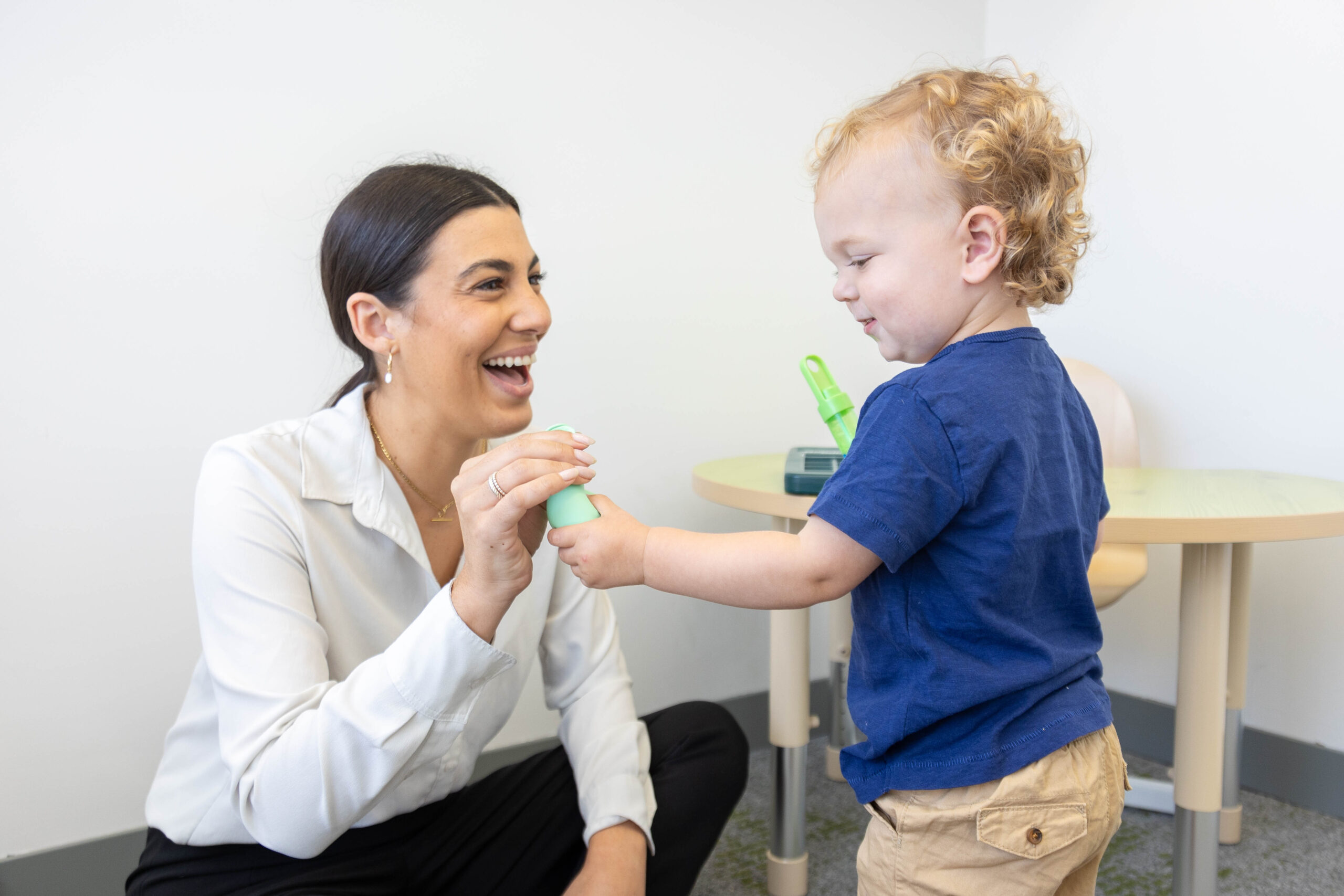 Woman joyfully interacts with a smiling toddler.